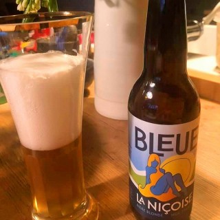 In a glass, a blonde beer. Next to it, a bottle of beer from the Brasserie Bleue